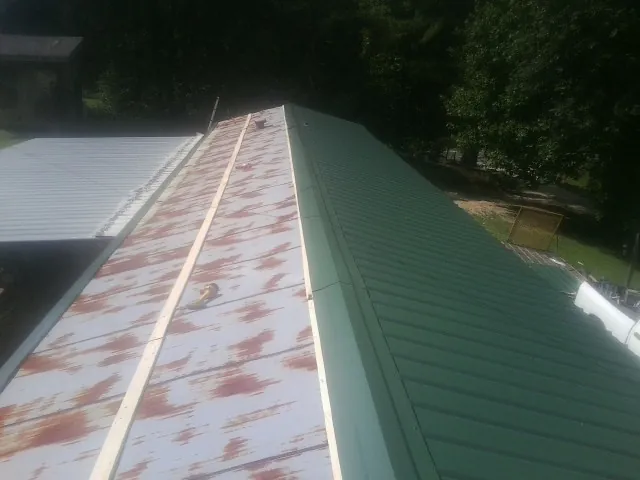 Old rusted panels beside newly installed green metal roofing — Wind Damage Roof Repair by Roofing Brothers in Alpine